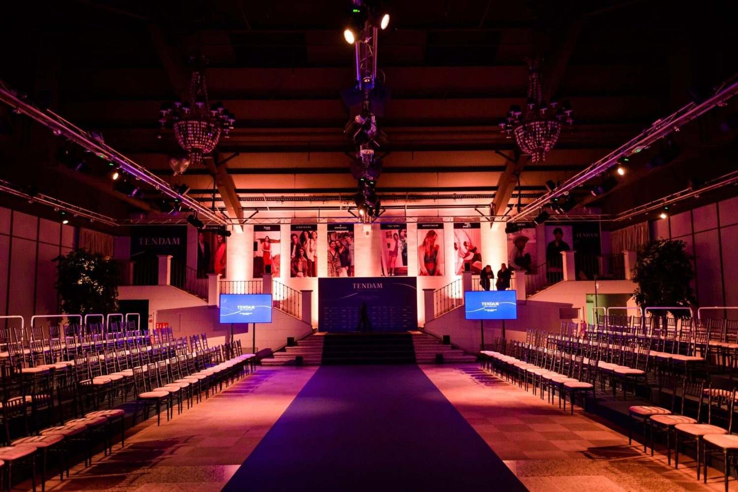 Pasarela de moda con sillas y luces en un evento de Tendam.