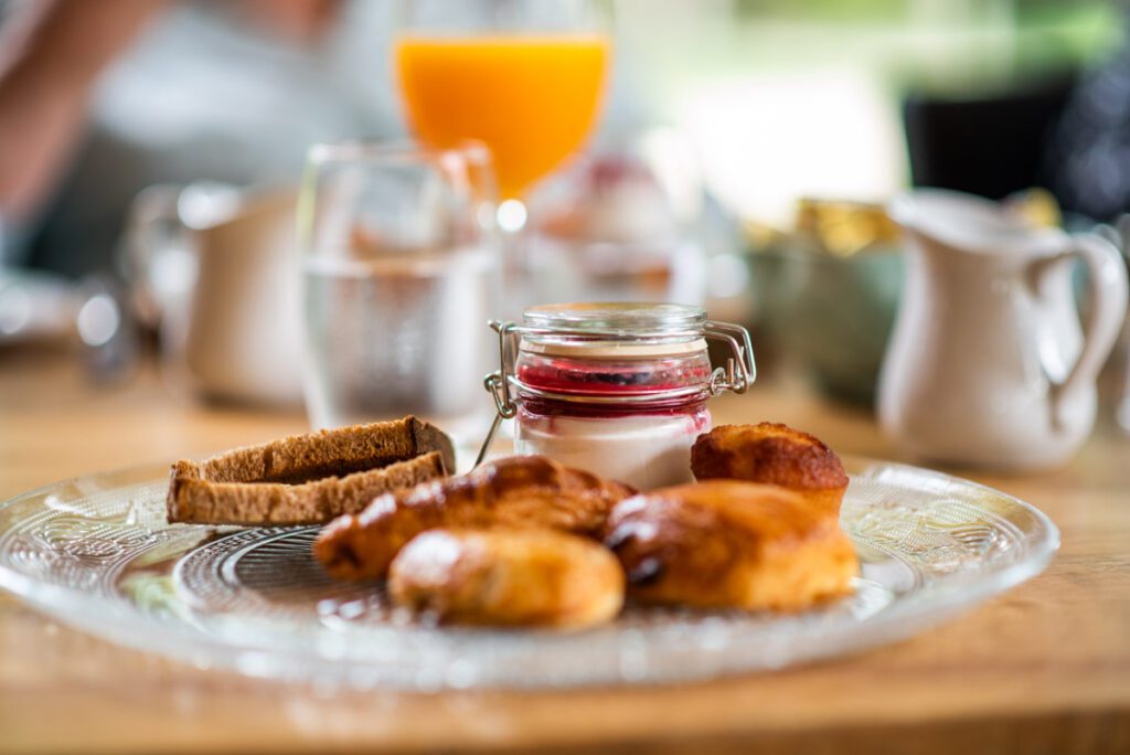 Desayuno con bollería, yogur con frutos rojos y jugo de naranja.