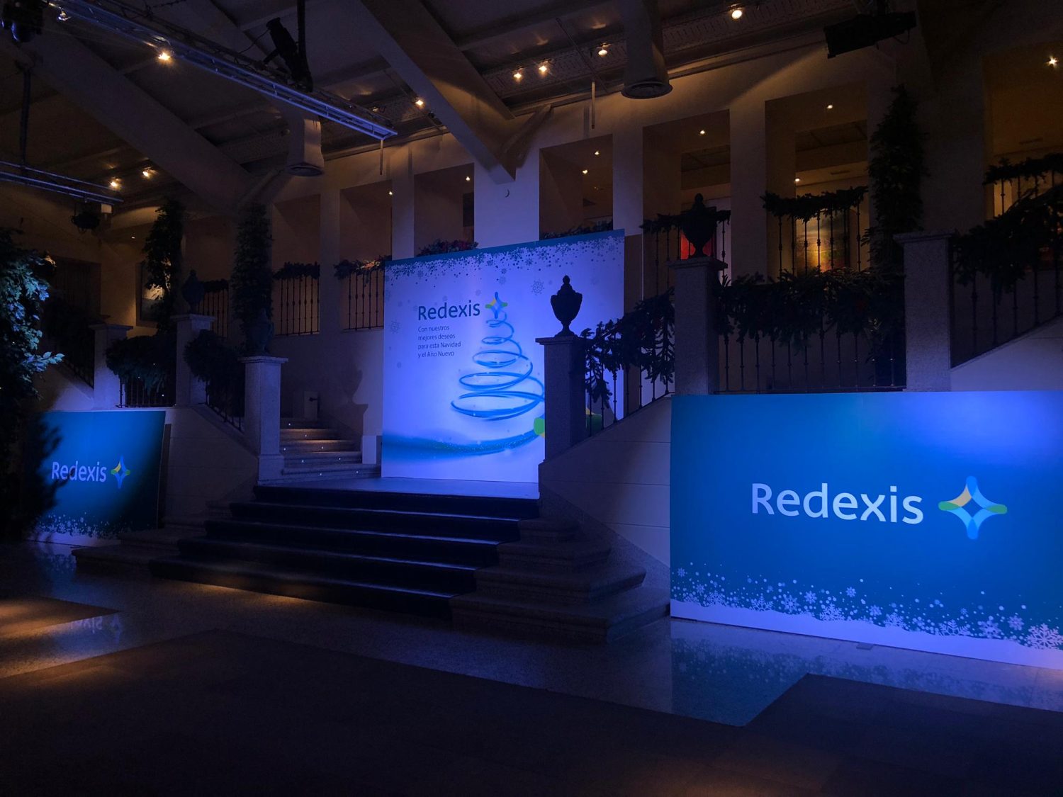 Escenario de evento Redexis con iluminación tenue y logotipo en banners azules.