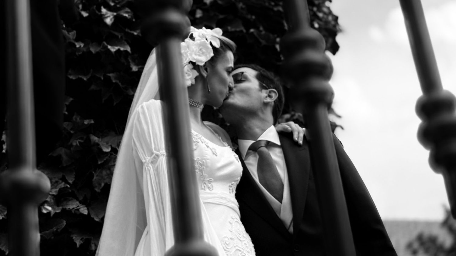 Foto en blanco y negro de los novios dándose un beso en los jardines de La Quinta de Jarama