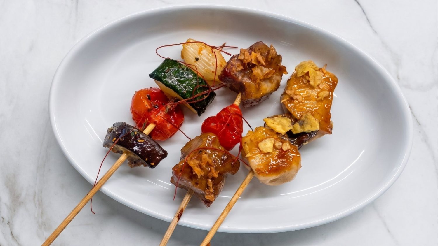 Elegantes brochetas de carne y verduras a la robata con salsa teriyaki, servidas como aperitivo en la estación asiática de La Quinta de Jarama.